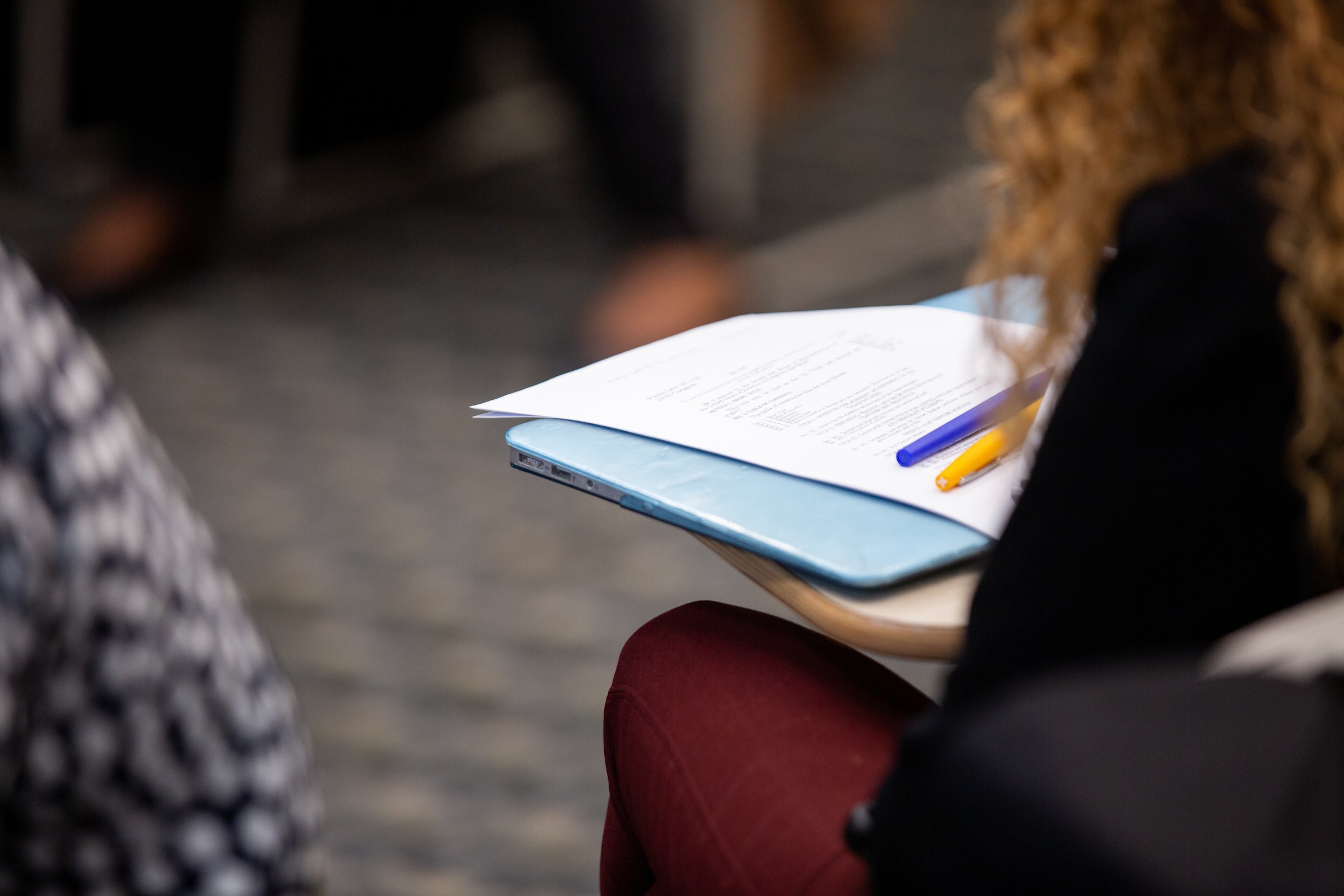 Student in a desk seat with a paper and writing instruments