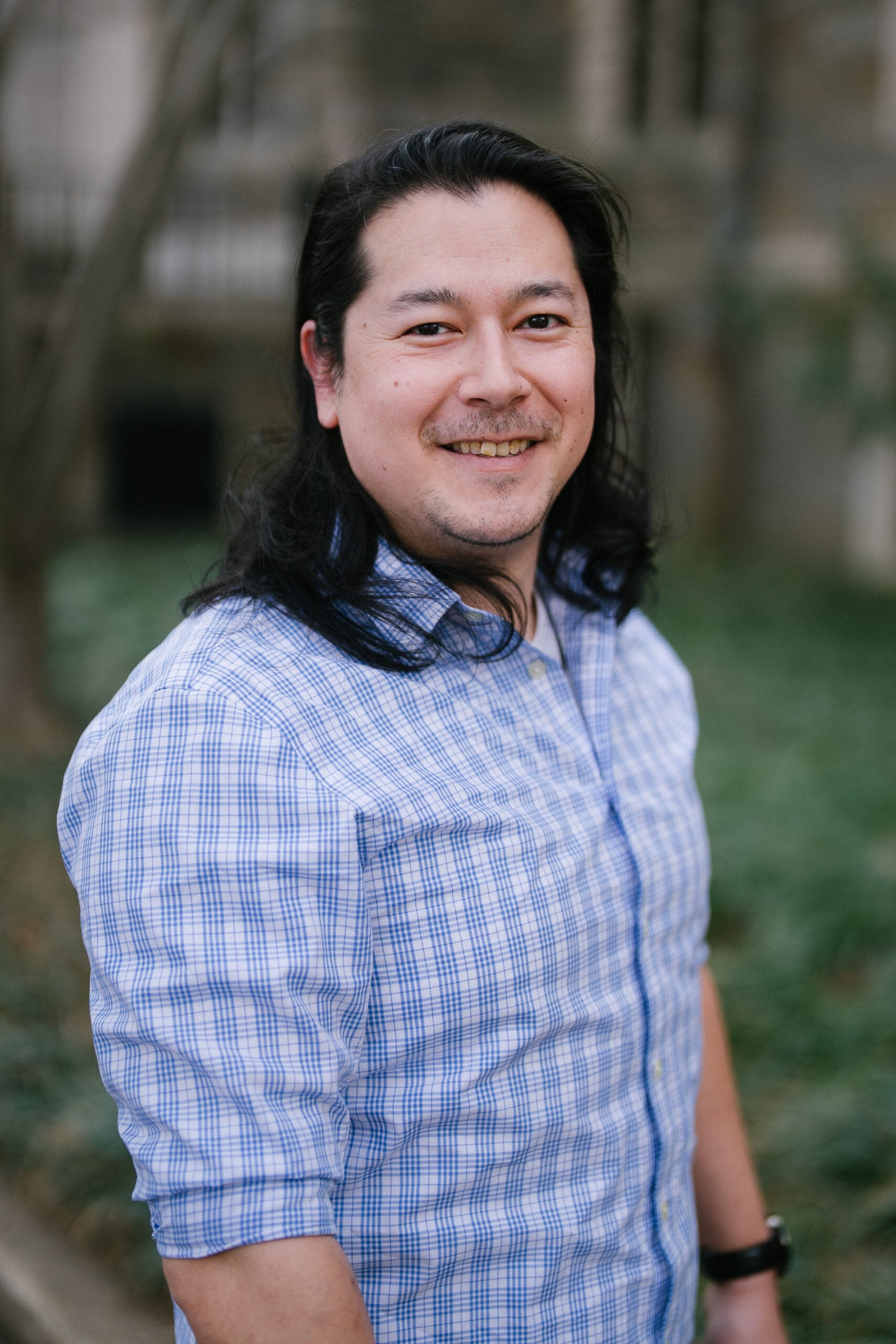 Portrait of an asian american man in a white and blue checkered shirt.